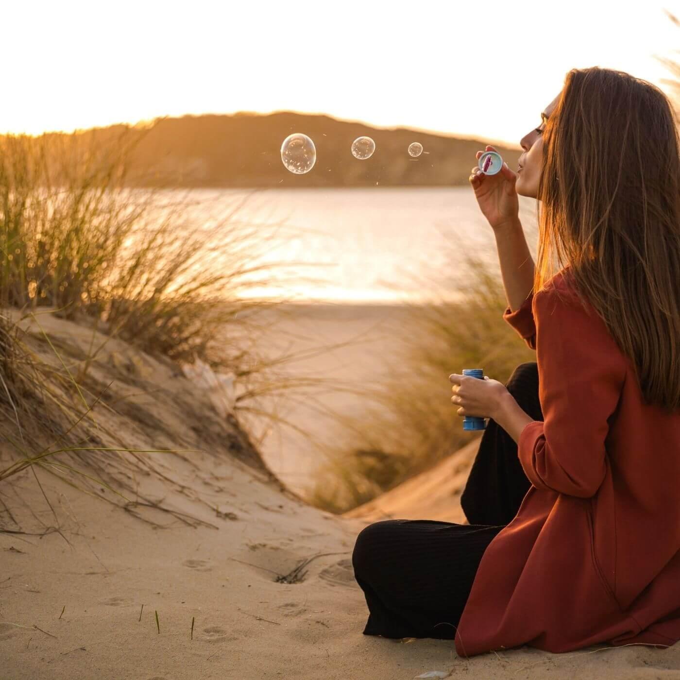 Woman on the beach blowing soap bubbles