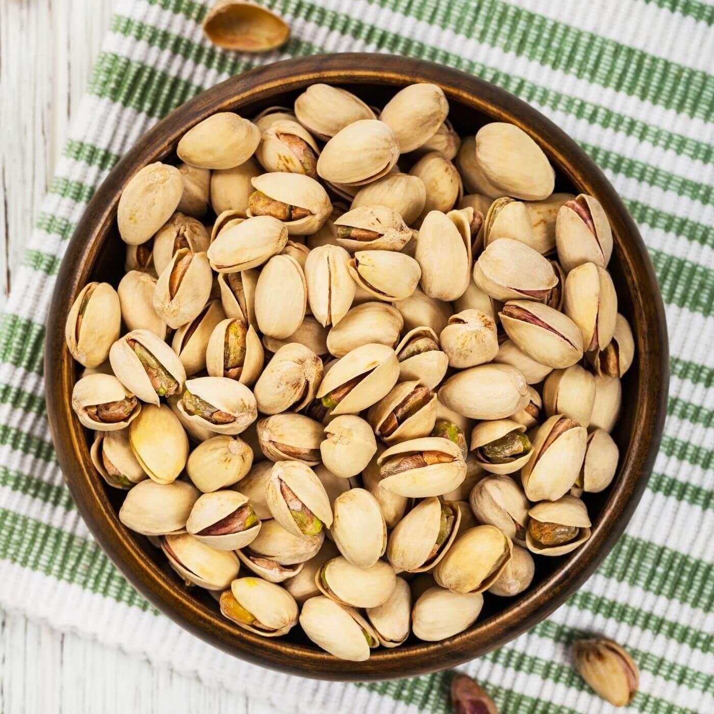 Bowl of pistachios on a striped green towel 